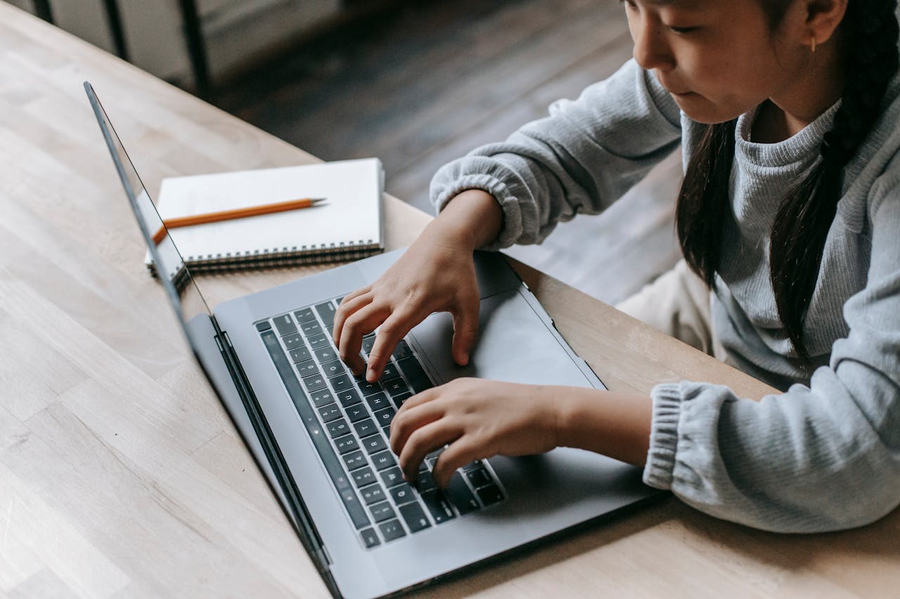 Young girl focused on studying with a laptop at home, enhancing her digital learning experience.