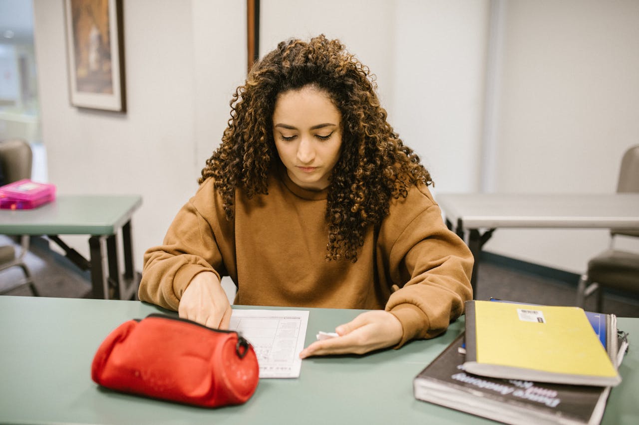 Young woman studying for an exam in a college classroom with books and notes.